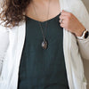 woman in blue and white top wearing healing crystal talisman necklace