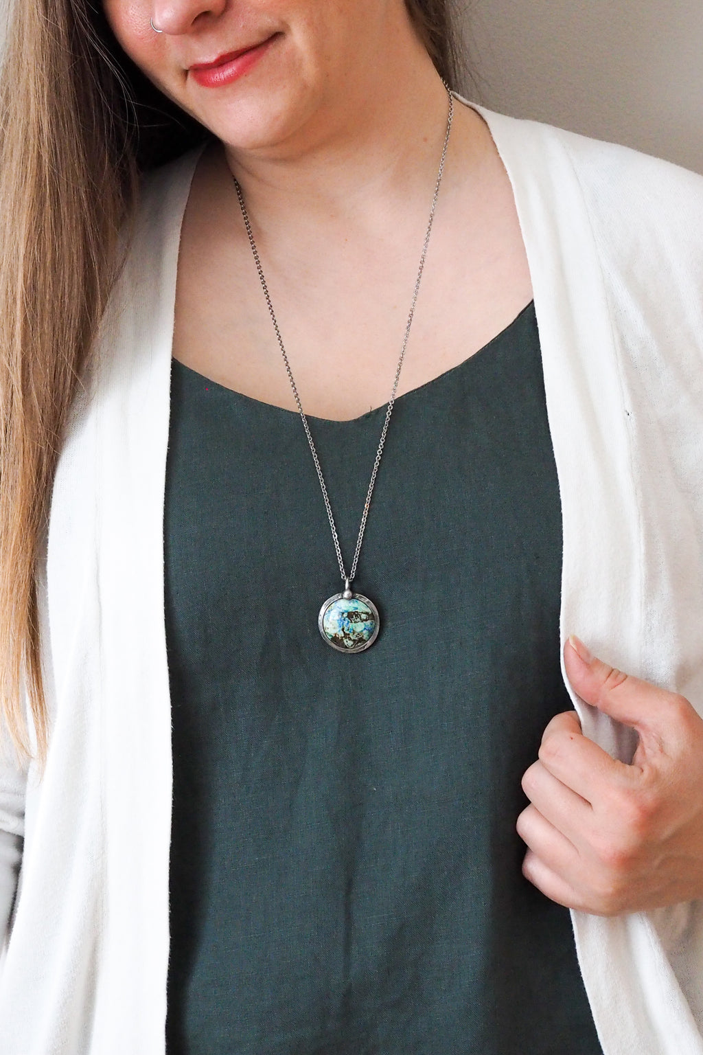 blue and green mixed gemstone healing crystal talisman statement necklace on woman in blue top with white cardigan