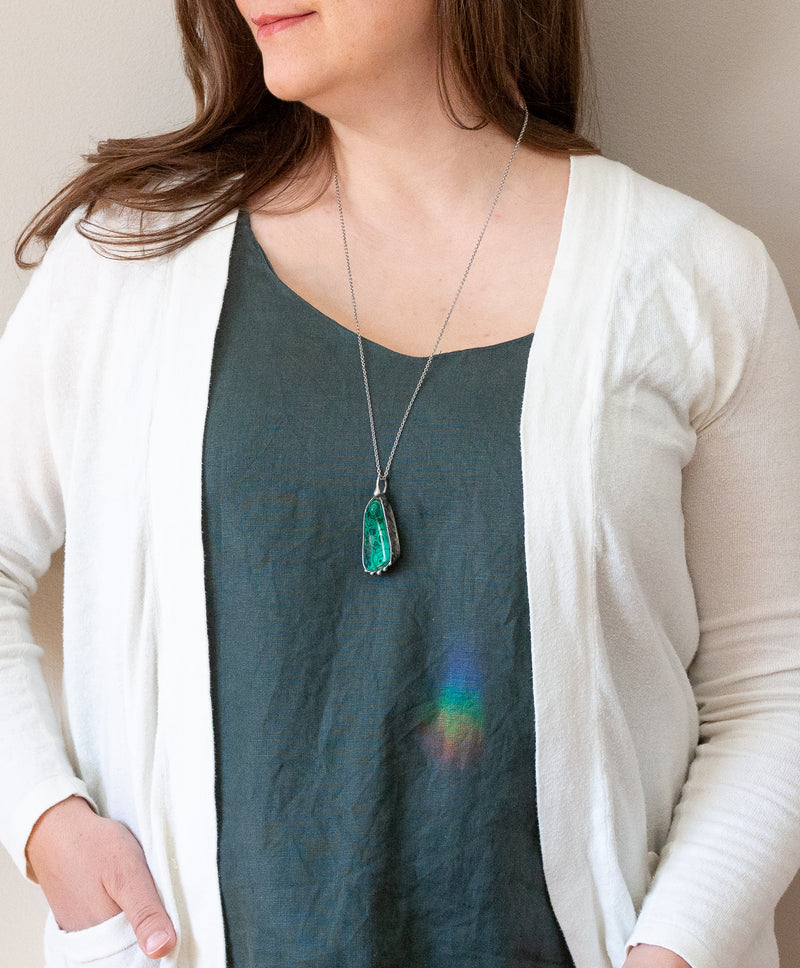 woman in blue top wearing brilliant green malachite talisman crystal necklace