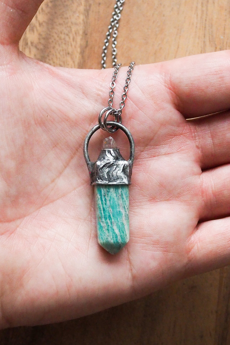 teal green gemstone healing crystal talisman necklace on palm of hand