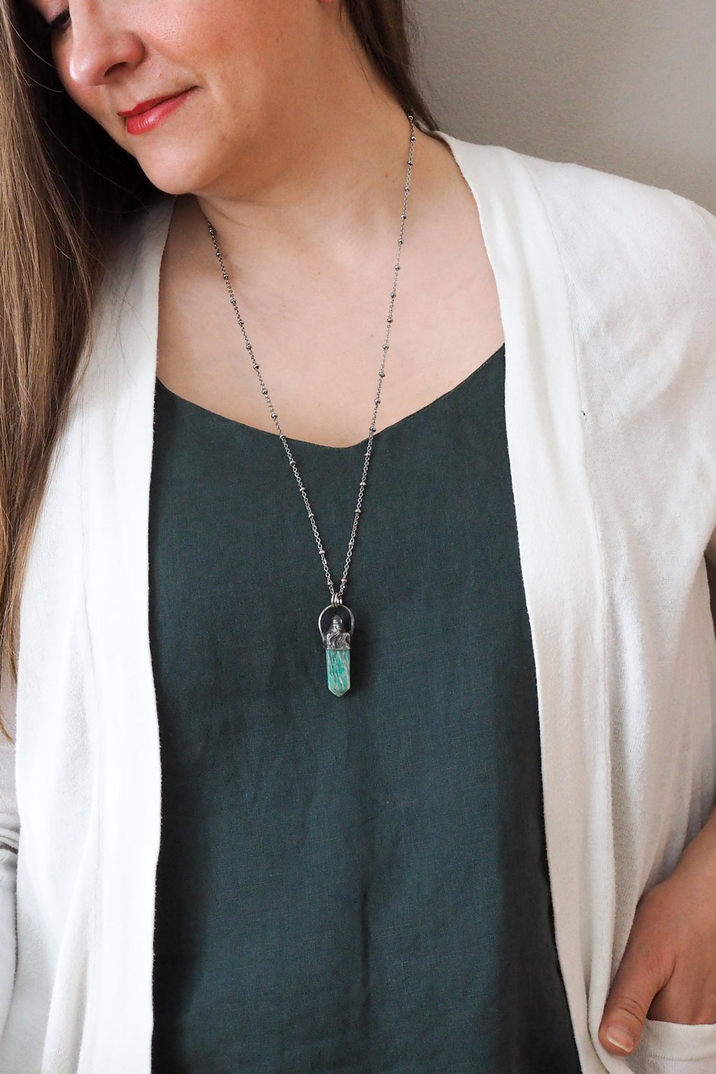 teal green gemstone healing crystal talisman necklace on woman in blue top with white cardigan