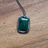 deep green malachite healing crystal talisman necklace on wooden background