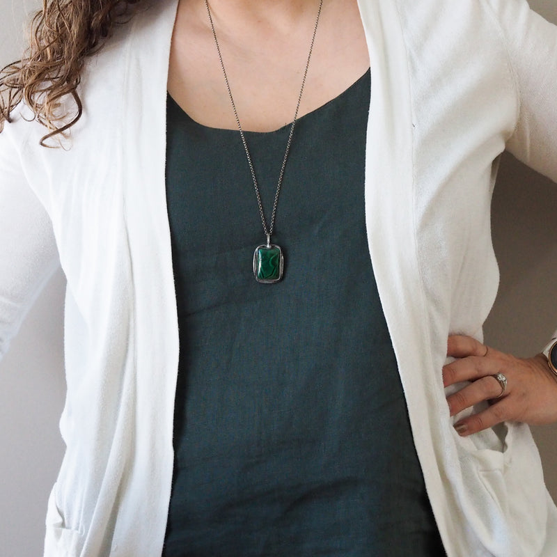 woman in blue and white top wearing deep green malachite healing crystal talisman necklace