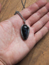 blue coffin shaped healing crystal talisman necklace in palm of hand