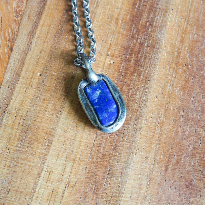 blue lapis lazuli healing crystal talisman necklace on wooden background