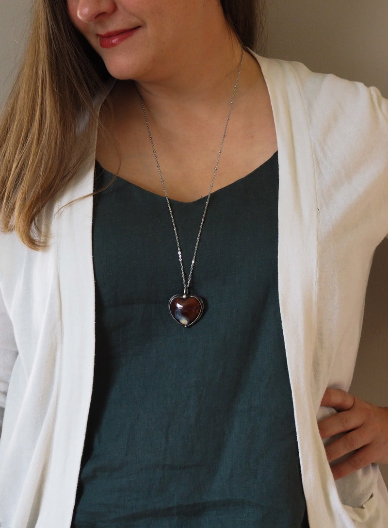 woman in blue top wearing red heart crystal healing talisman statement necklace