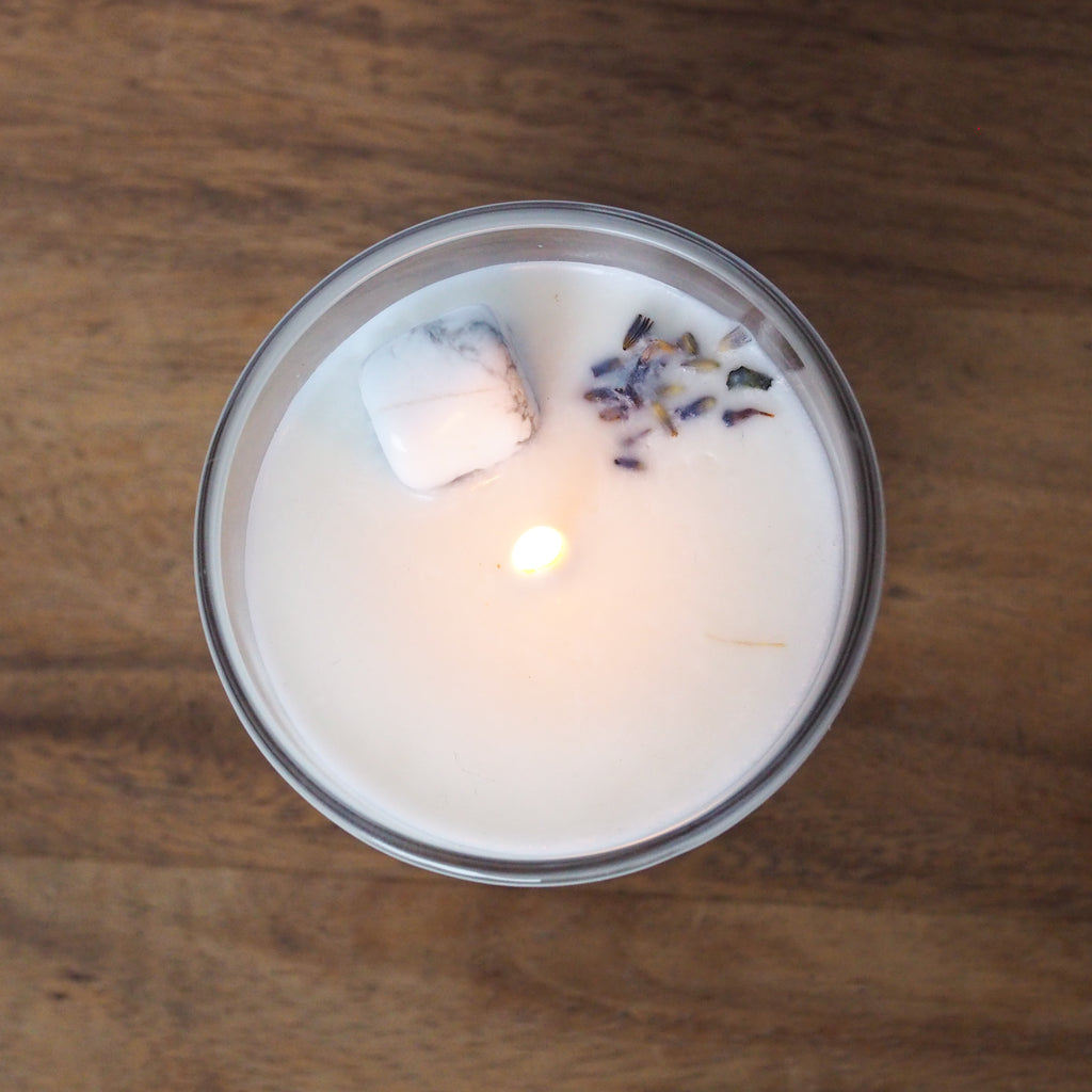 top view of lit libra zodiac candle with white howlite crystal and botanicals