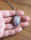 soft purple gemstone crystal talisman necklace in palm of hand