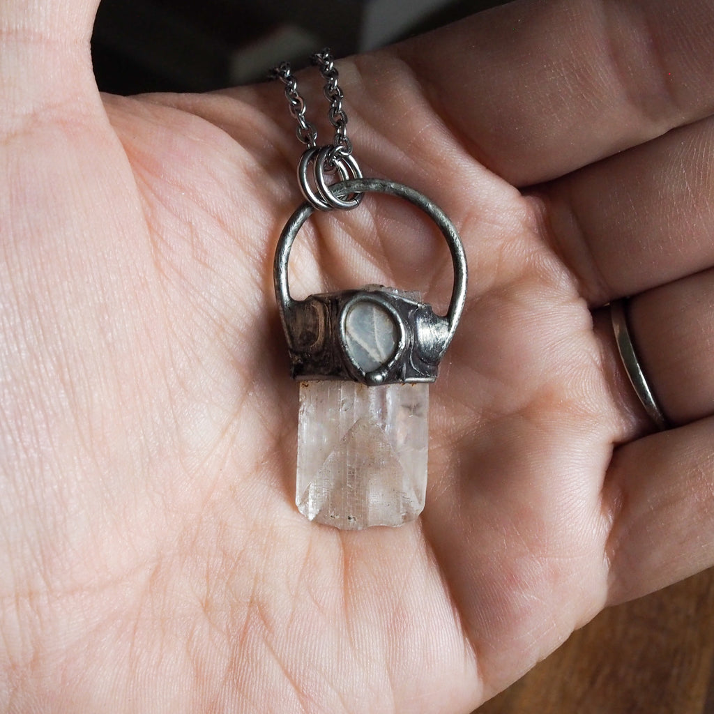 pale pink and white healing crystal talisman necklace in palm of hand