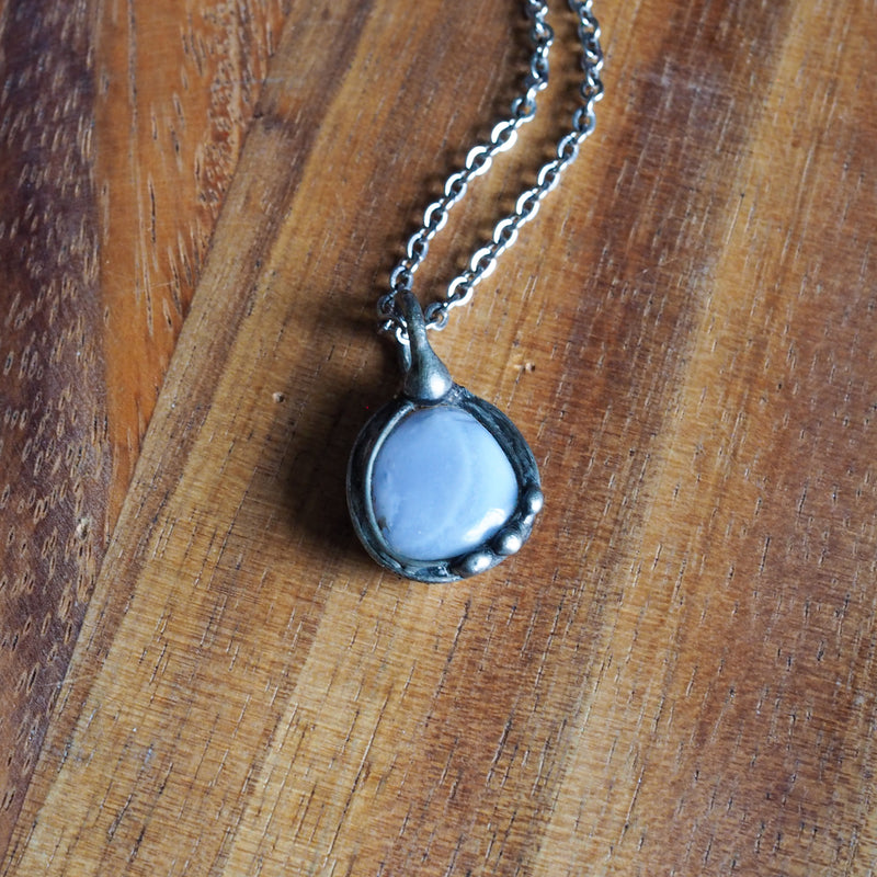 pale blue healing crystal talisman necklace on wooden background