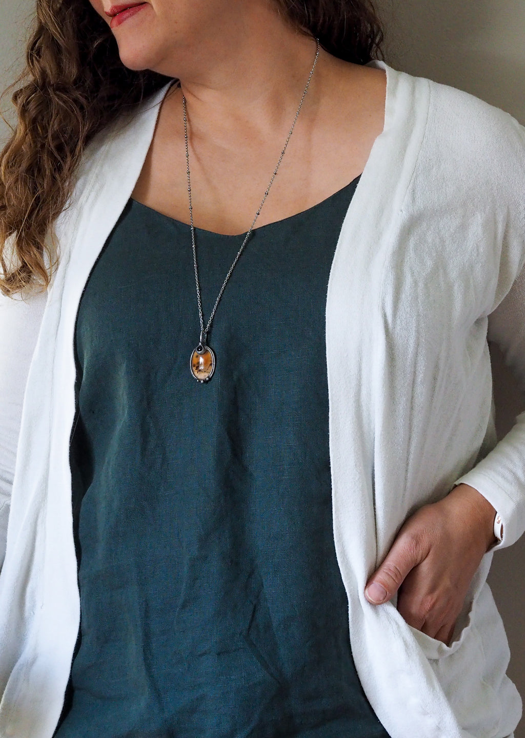 orange crystal talisman necklace on woman in blue top