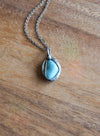 light blue gemstone crystal necklace talisman on wooden background