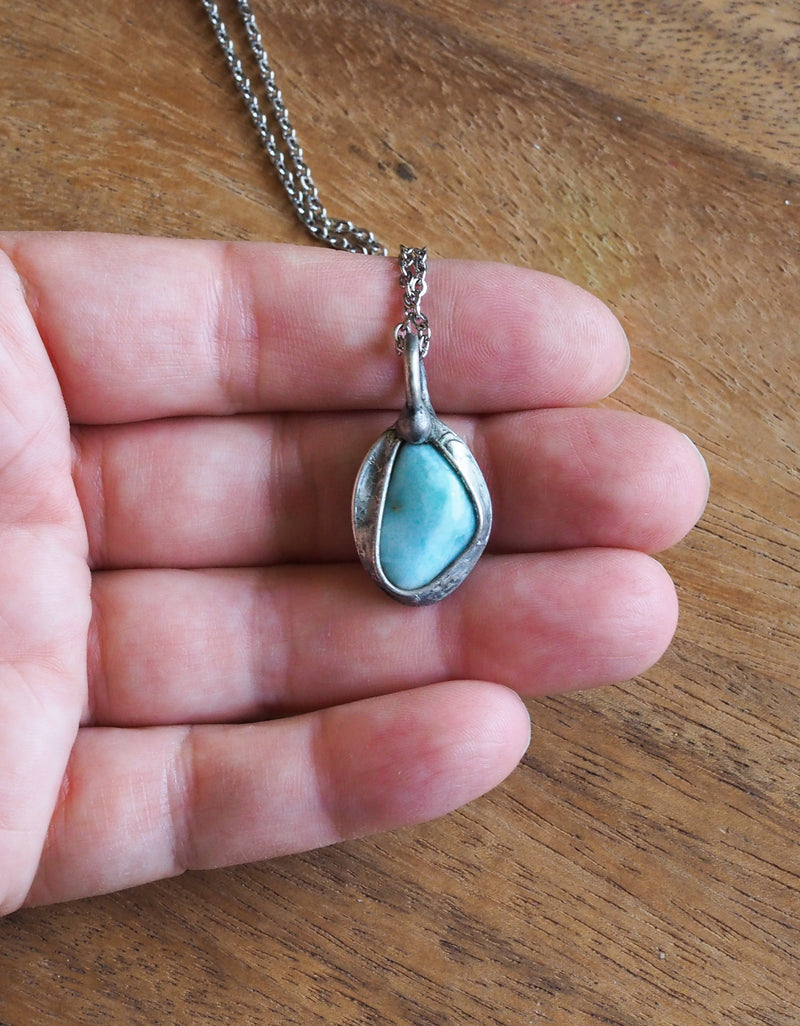 light blue gemstone crystal necklace talisman in palm of hand