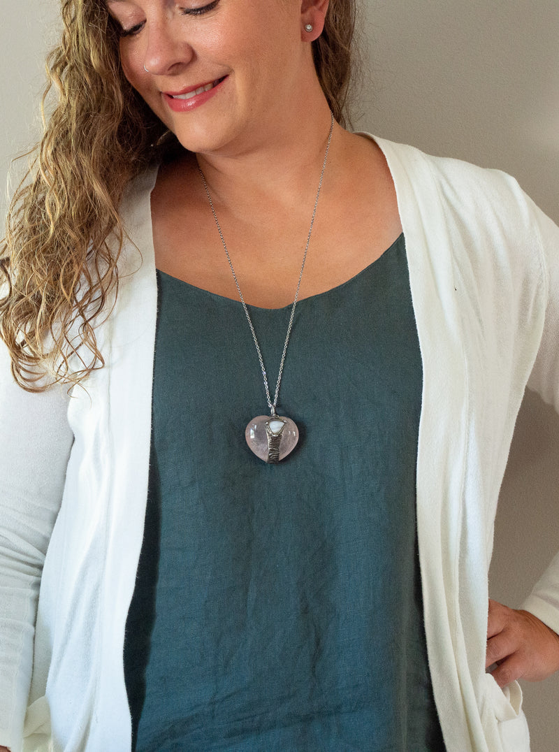 soft pink and blue gemstone talisman necklace on woman with blue top and white cardigan