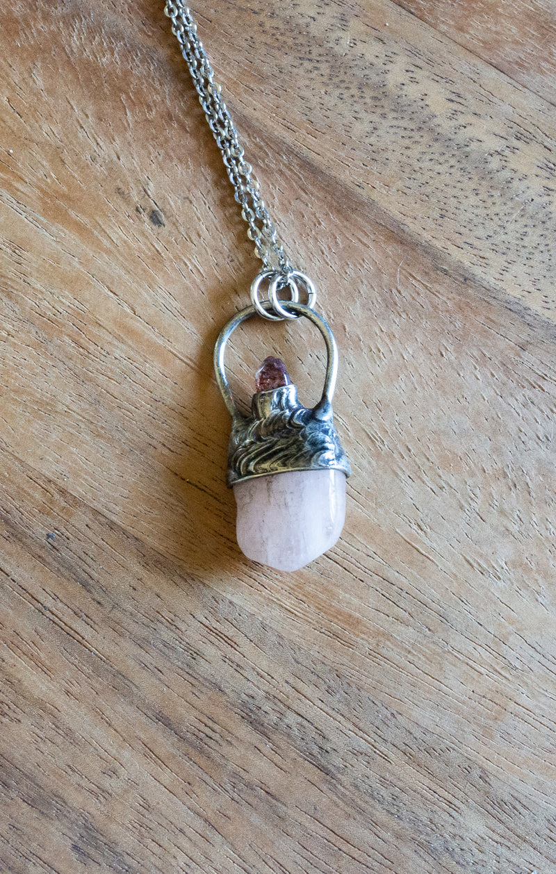 soft pink and red raw gemstone crystal talisman necklace on woman in blue and white top