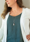 soft pink raw gemstone crystal talisman necklace on woman in blue and white top