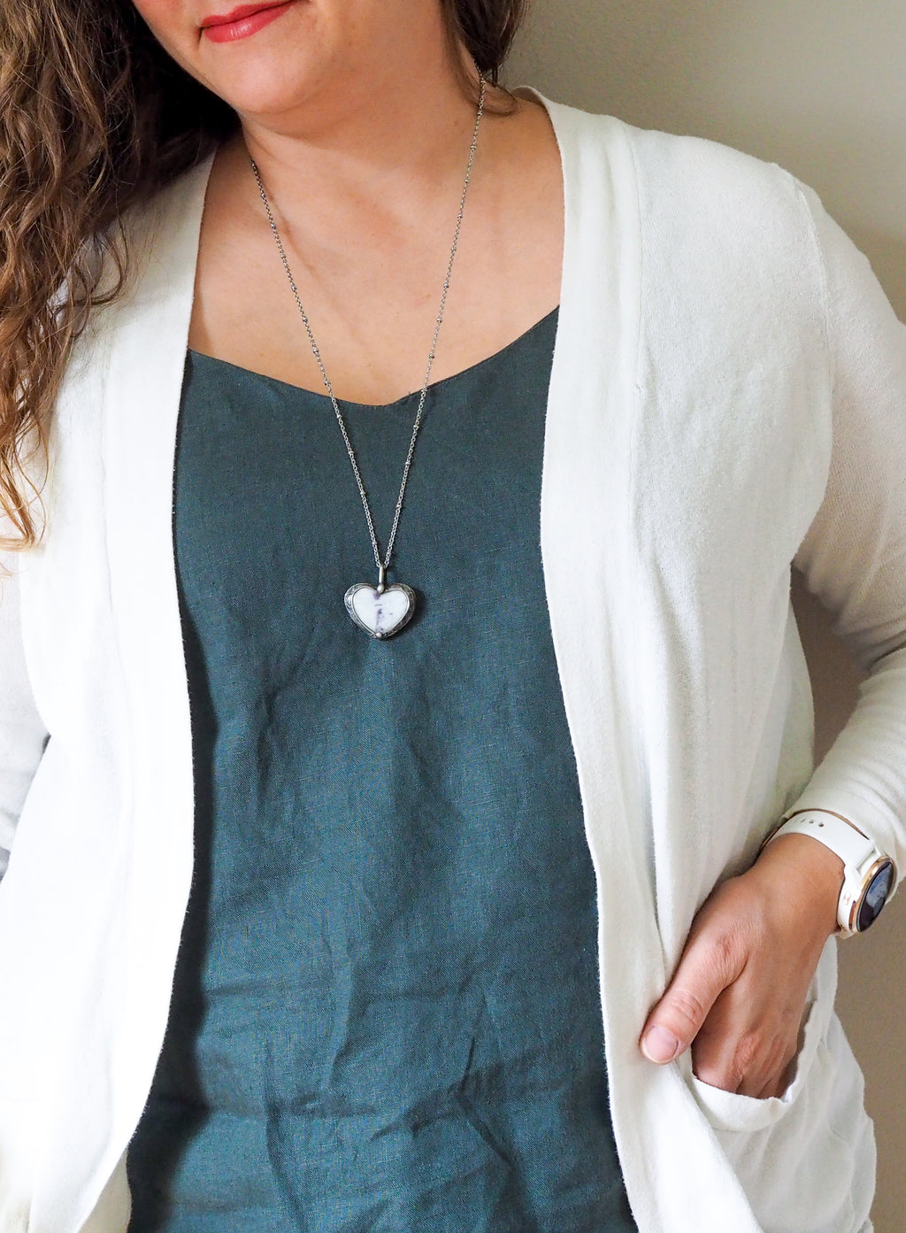 purple and sparkly white heart shaped healing crystal talisman necklace on woman in blue top