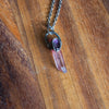 purple healing crystal talisman necklace on wooden background