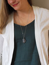 woman in blue top wearing clear and black healing crystal talisman statement necklace
