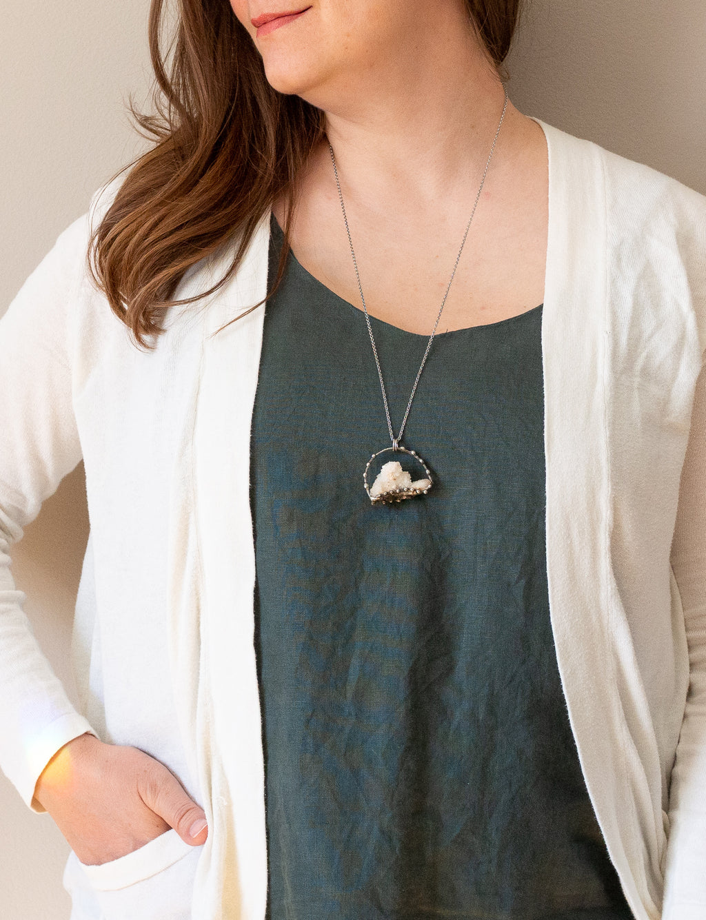 white sparkly spirit quartz raw gemstone crystal talisman necklace on woman in blue top with white cardigan