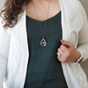 woman in blue and white top wearing healing crystal talisman necklace