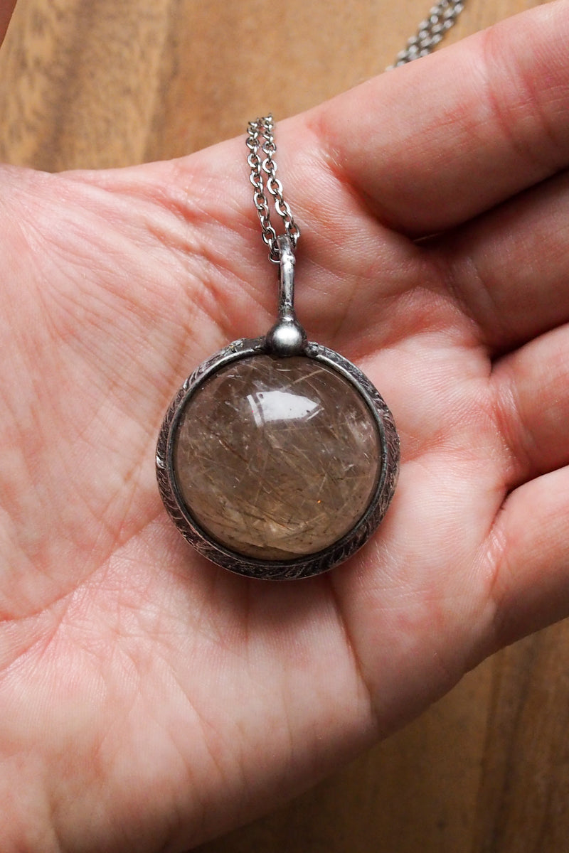 rustic chunky crystal orb layering talisman necklace in palm of hand