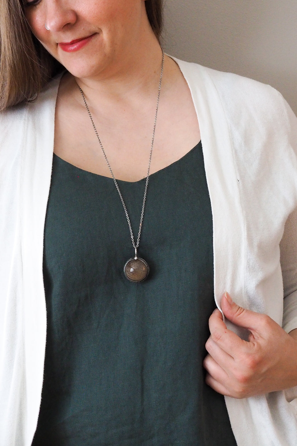 rustic chunky crystal orb layering talisman necklace on model wearing blue top and white cardigan