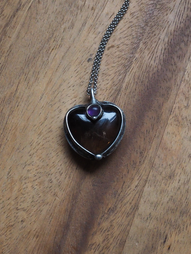 grey and purple heart shaped healing crystal talisman statement necklace on wooden backdrop