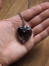 hand holding grey and purple heart shaped healing crystal talisman statement necklace