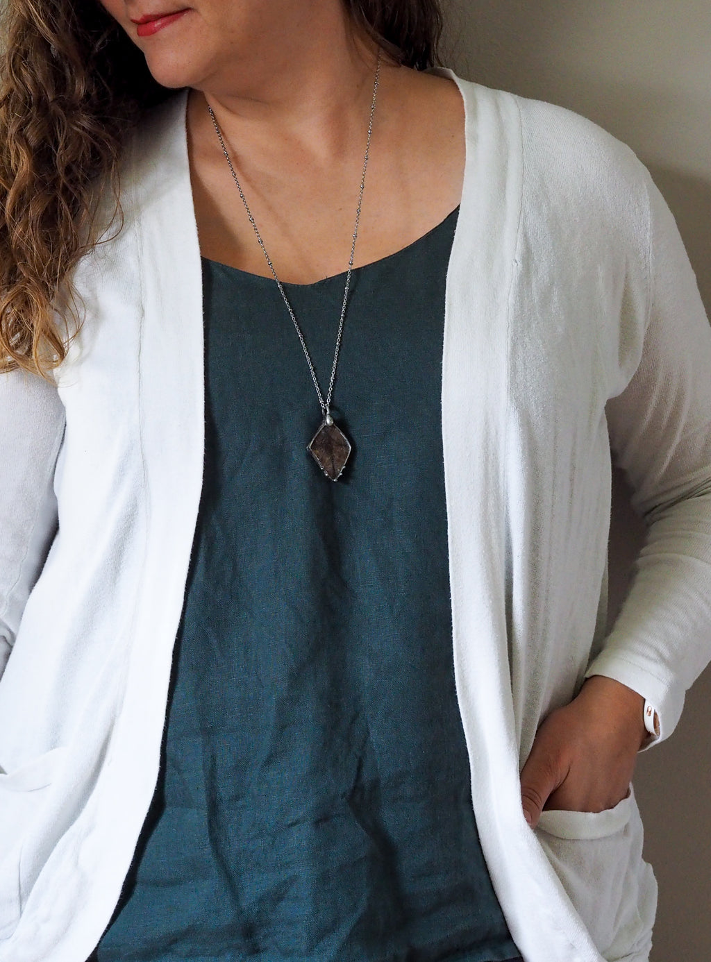 brown crystal talisman necklace on woman in blue top