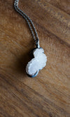 sparkly white healing crystal talisman necklace on wooden background