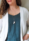 sparkly white healing crystal talisman necklace on woman in blue top