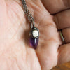 purple and white healing crystal talisman necklace in palm of hand