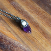 purple and white healing crystal talisman necklac on woodem background