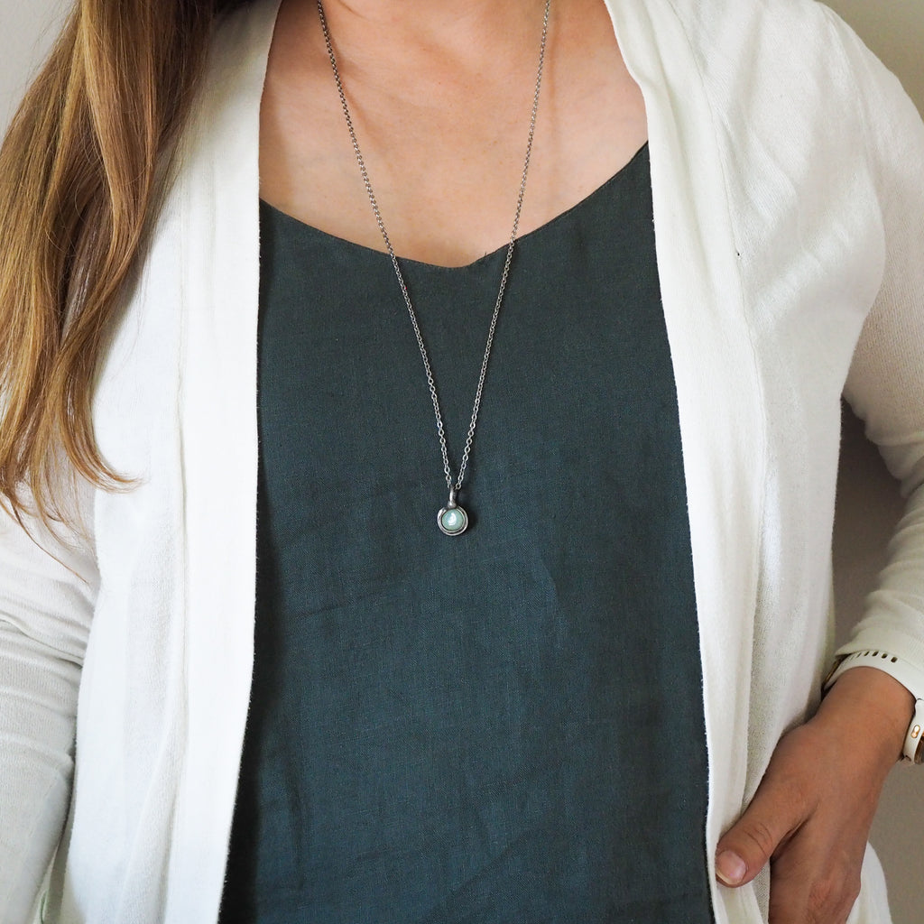 green healing crystal talisman necklace on woman in blue top