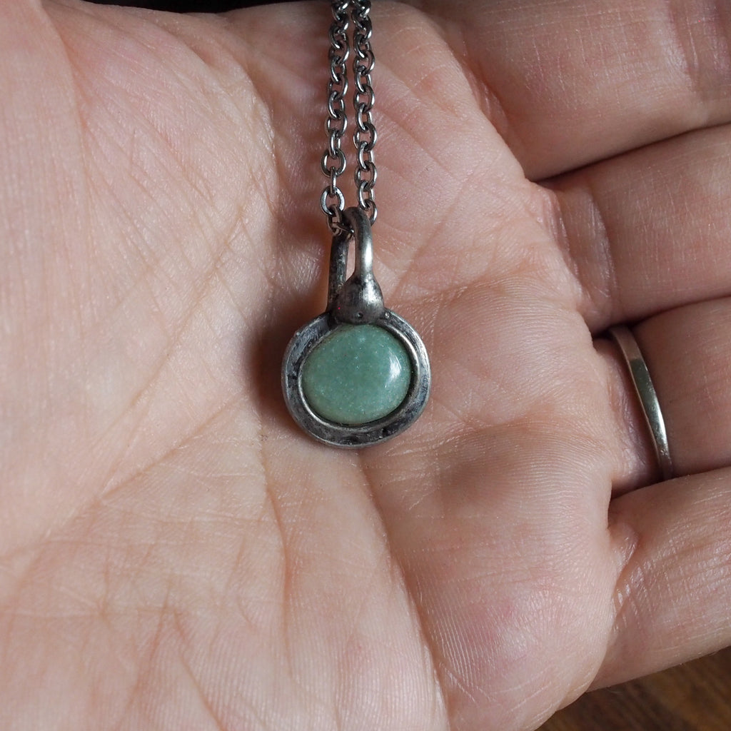 green healing crystal talisman necklace in palm of hand