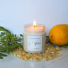 lit summer solstice soy crystal intention candle with greenery, citrus fruit, and crystals