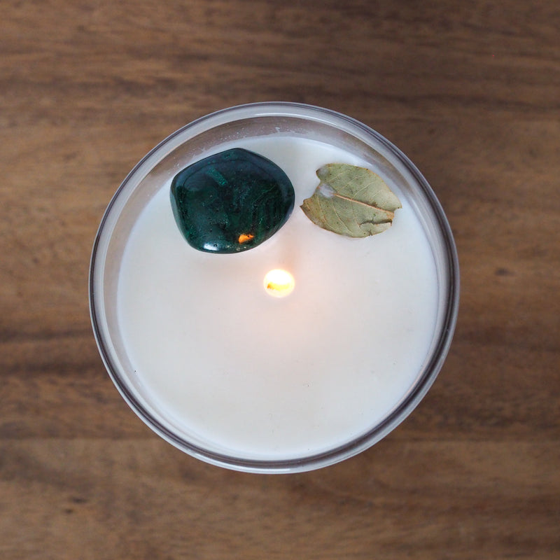 lit top view taurus candle with green malachite crystal and botanicals