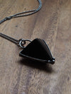 black triangle crystal talisman statement necklace on wooden background