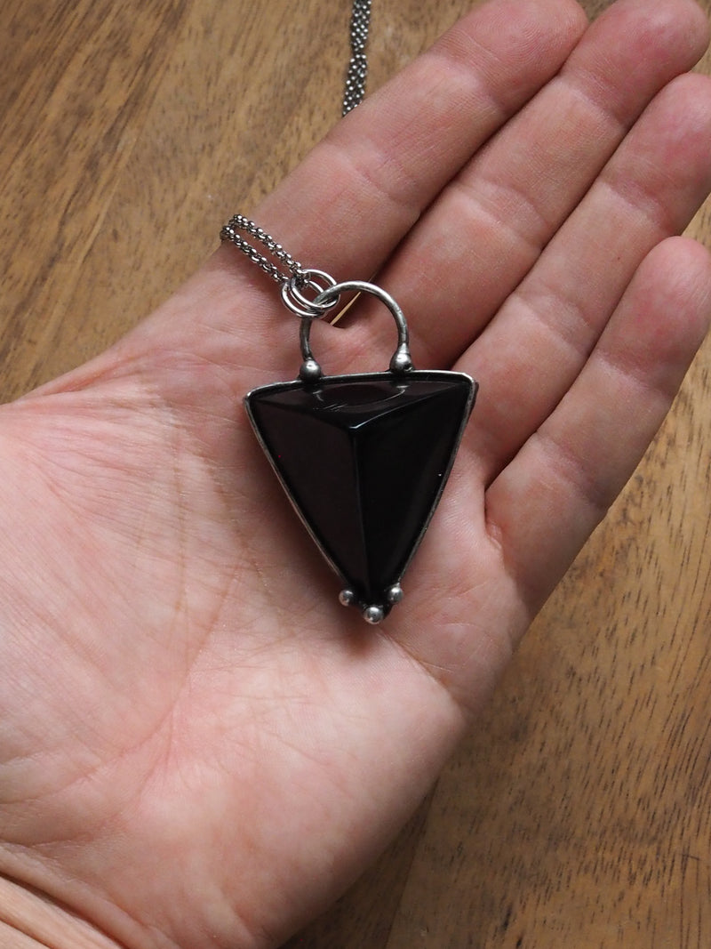 hand holding black triangle crystal talisman statement necklace