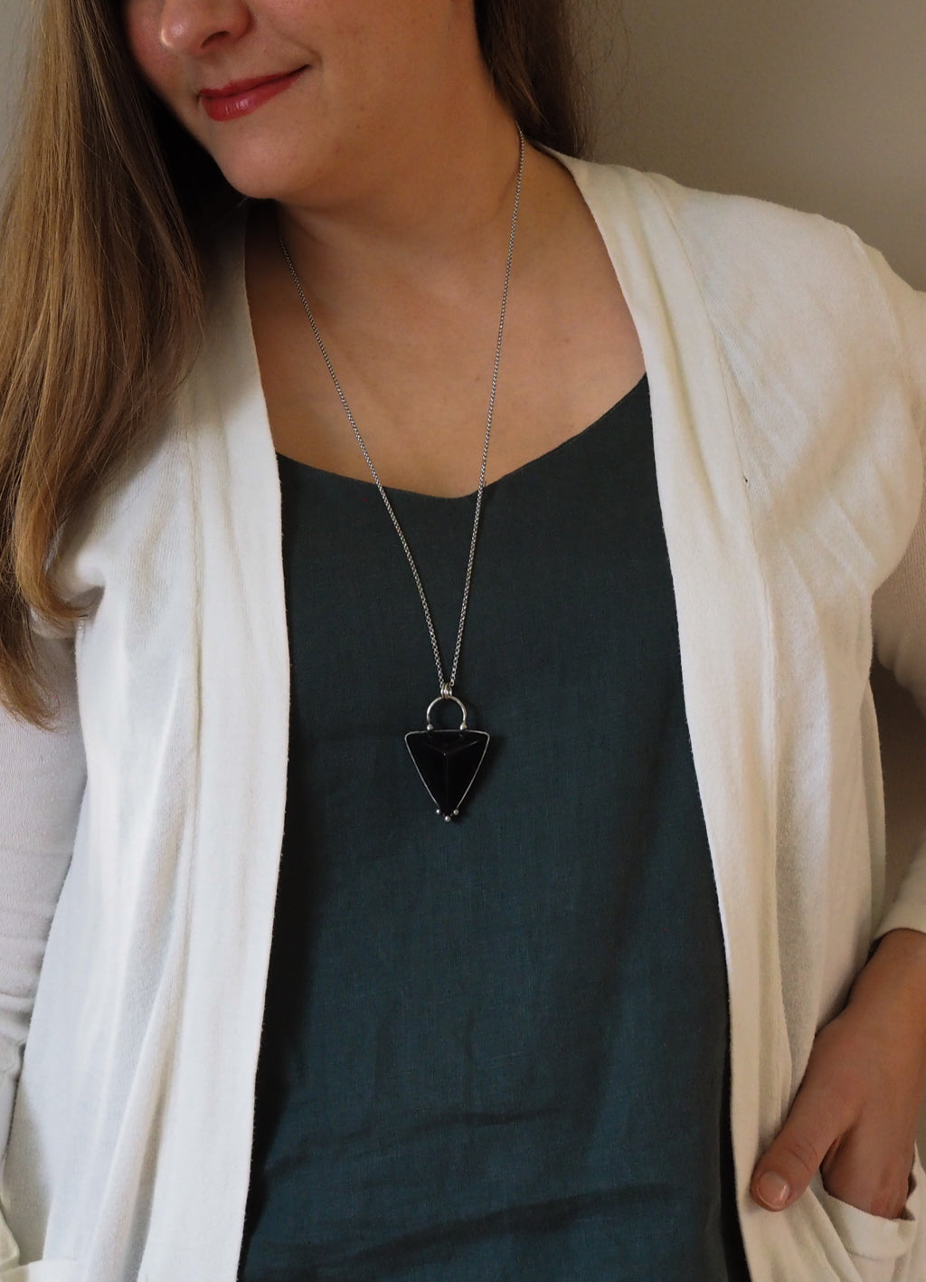 woman in blue top wearing black triangle crystal talisman statement necklace