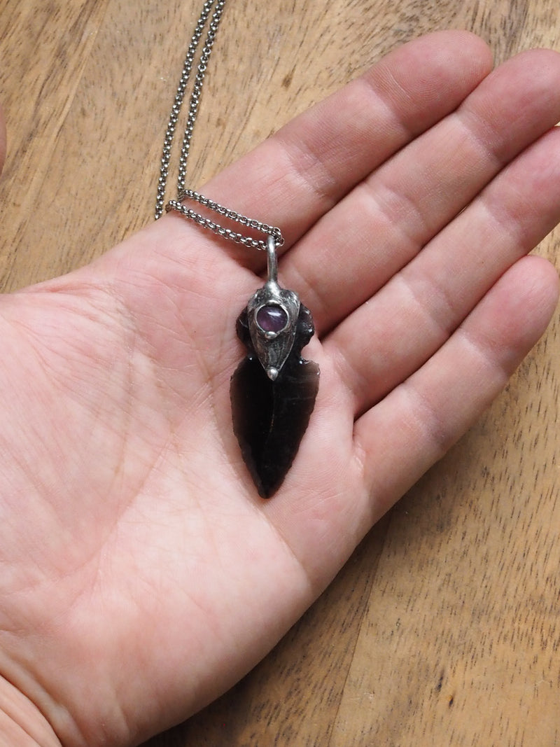 hand holding black and purple arrowhead healing crystal talisman statement necklace