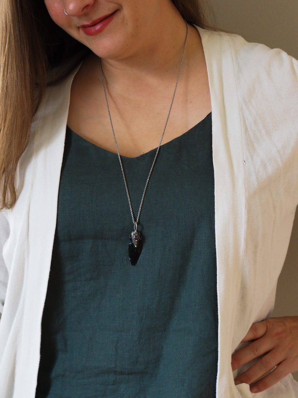 woman in blue top wearing black arrowhead healing crystal talisman statement necklace