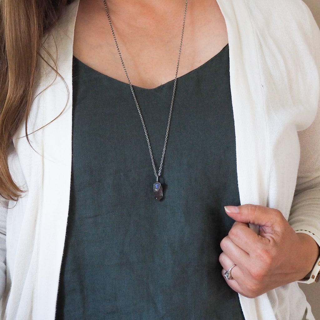 clear and blue healing crystal talisman necklace on woman in blue top