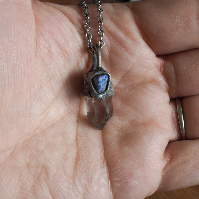clear and blue healing crystal talisman necklace  in palm of hand