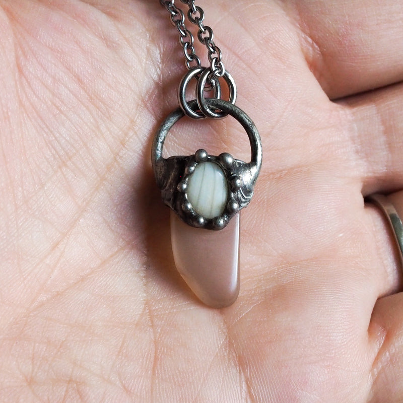 peach moonstone healing crystal talisman necklace in palm of hand