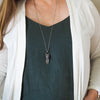 clear and purple healing crystal talisman necklace on woman in blue top