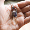 clear and purple healing crystal talisman necklace in palm of hand