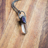 clear and purple healing crystal talisman necklace on wooden background