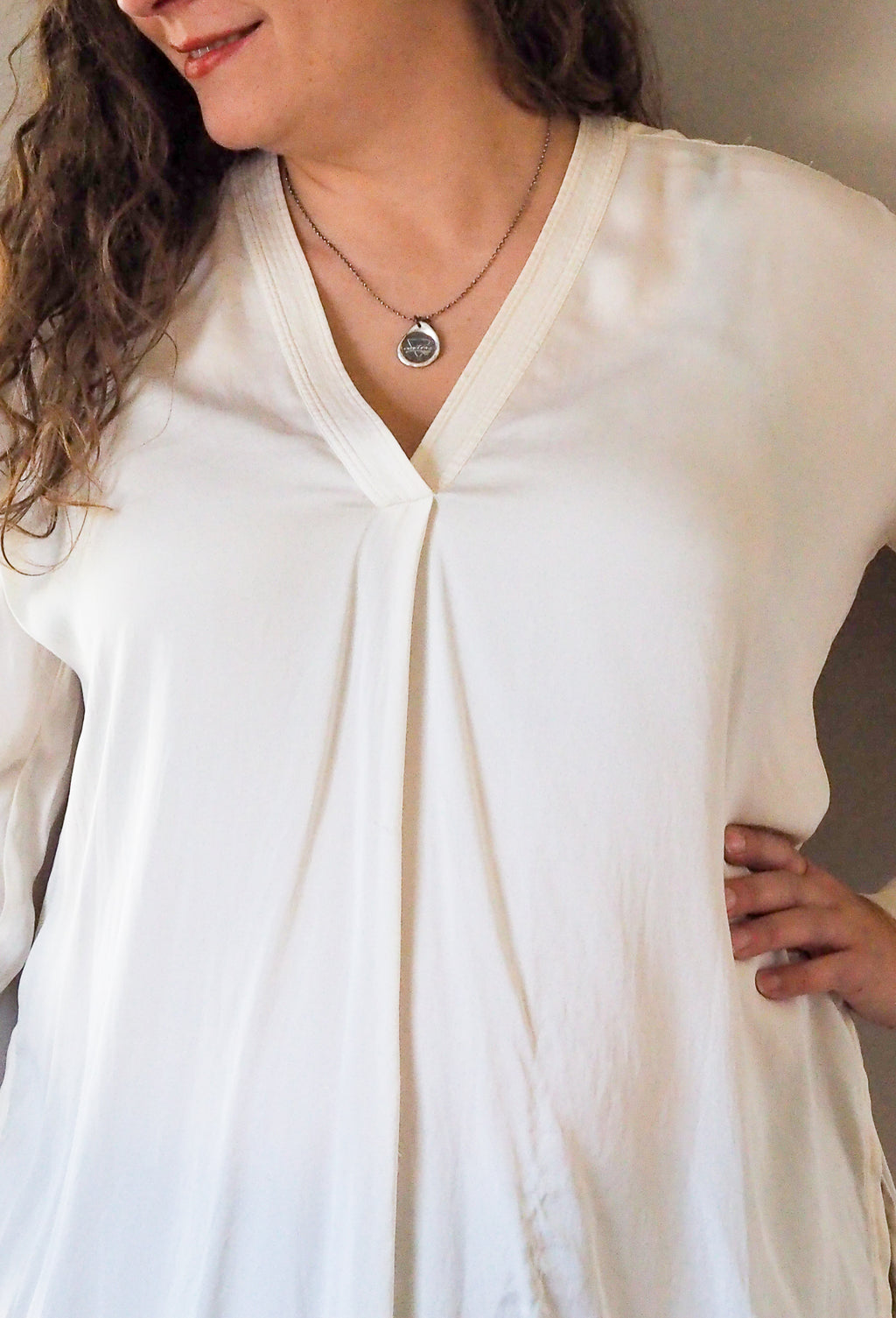 silver water sign necklace on woman in white silk top